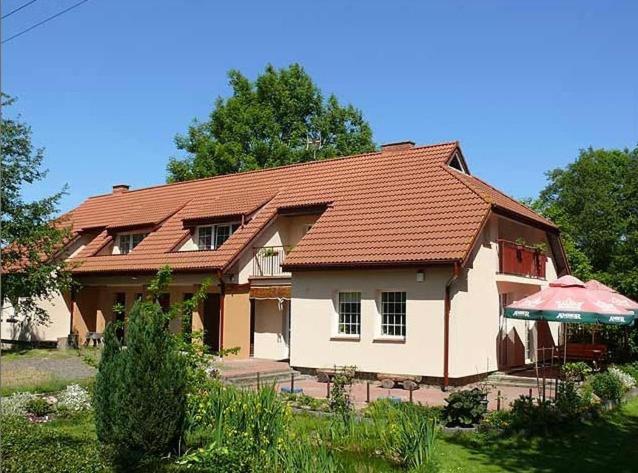 una casa con techo rojo y sombrilla en Pokoje Gościnne POD KNOTEM, en Karwieńskie Błoto Drugie