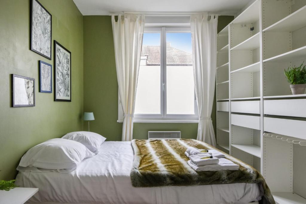 een groene slaapkamer met een bed en een raam bij T2 - parking et jardin privatif in Lambersart