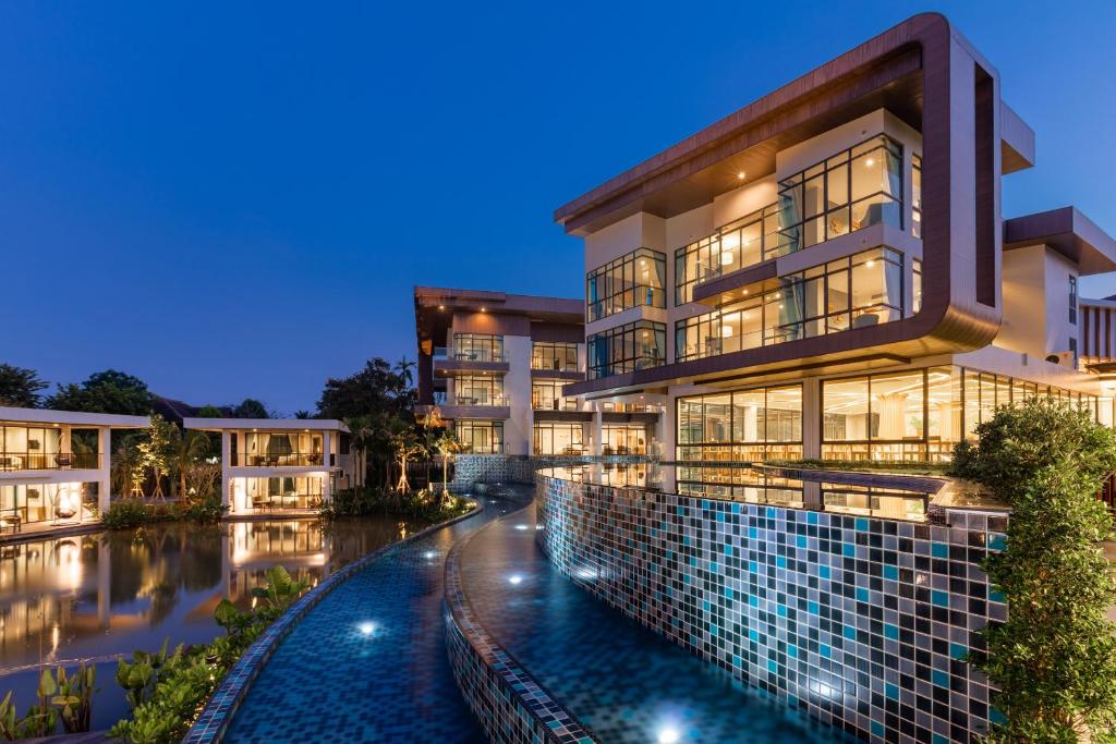 a building with a pool in front of it at Na Tree Tara Riverside Resort Amphawa Damnoensaduak in Amphawa