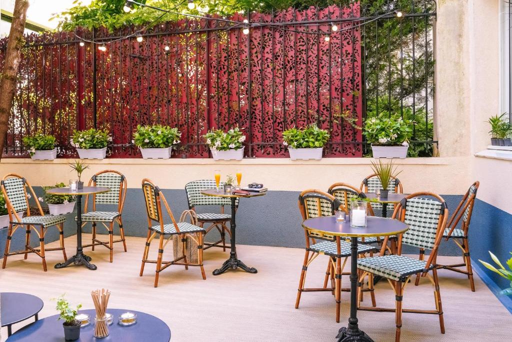 um pátio com mesas e cadeiras e uma cerca com plantas em Timhotel Tour Eiffel em Paris