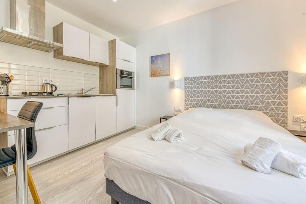 - une chambre blanche avec un grand lit et une cuisine dans l'établissement 44 Foch 3, à Grenoble