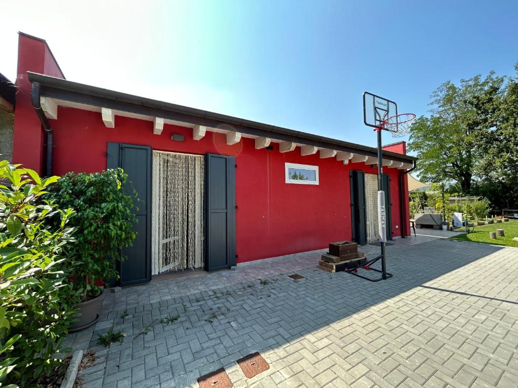 Um edifício vermelho com um cesto de basquetebol à frente. em Casetta rossa em Lesignano deʼ Bagni