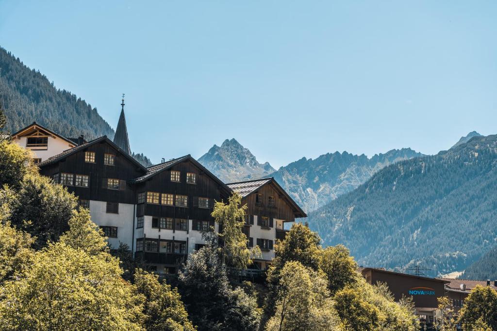a building on a hill with mountains in the background at Felbermayer Appartements in Gaschurn