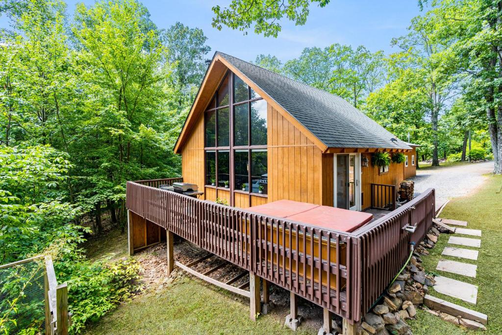 a cabin in the woods with a large window at Quaint Cabin w Hot Tub Firepit & Deck in Hedgesville