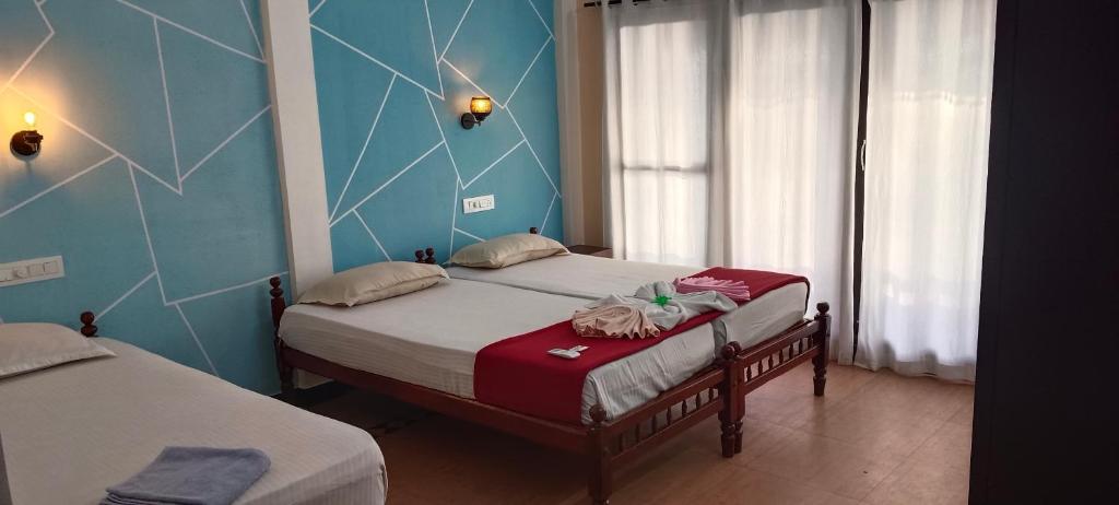 two twin beds in a room with blue walls at Cherai Ocean View Home in Cherai Beach