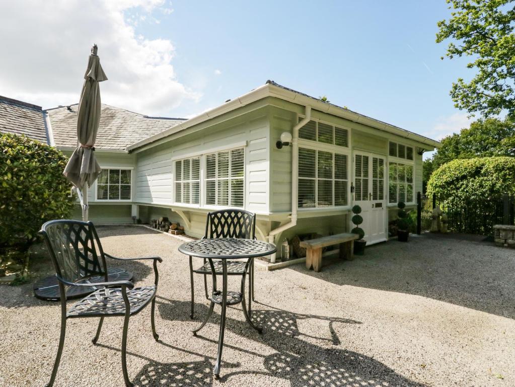 patio ze stołem i krzesłami oraz dom w obiekcie Woodland Lodge w mieście Grange-over-Sands