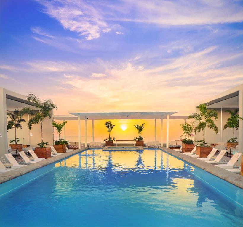 a swimming pool with chairs and a sunset in the background at Hotel Mio Vallarta Unique & Different- Adults Only in Puerto Vallarta
