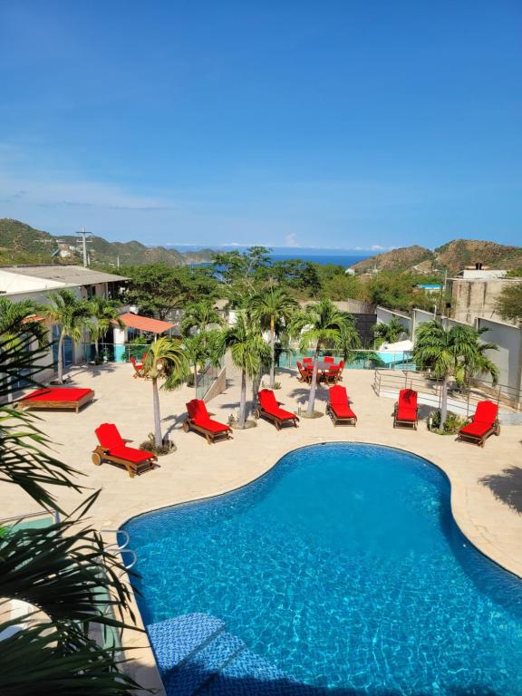 a resort with a swimming pool and chairs and the beach at Hotel Med Taganga in Taganga