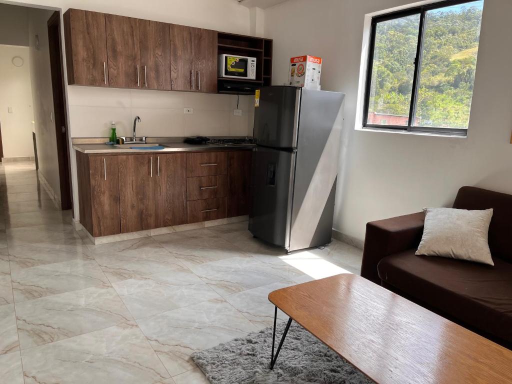 a kitchen with a refrigerator and a couch and a table at Apartamento in Sabaneta