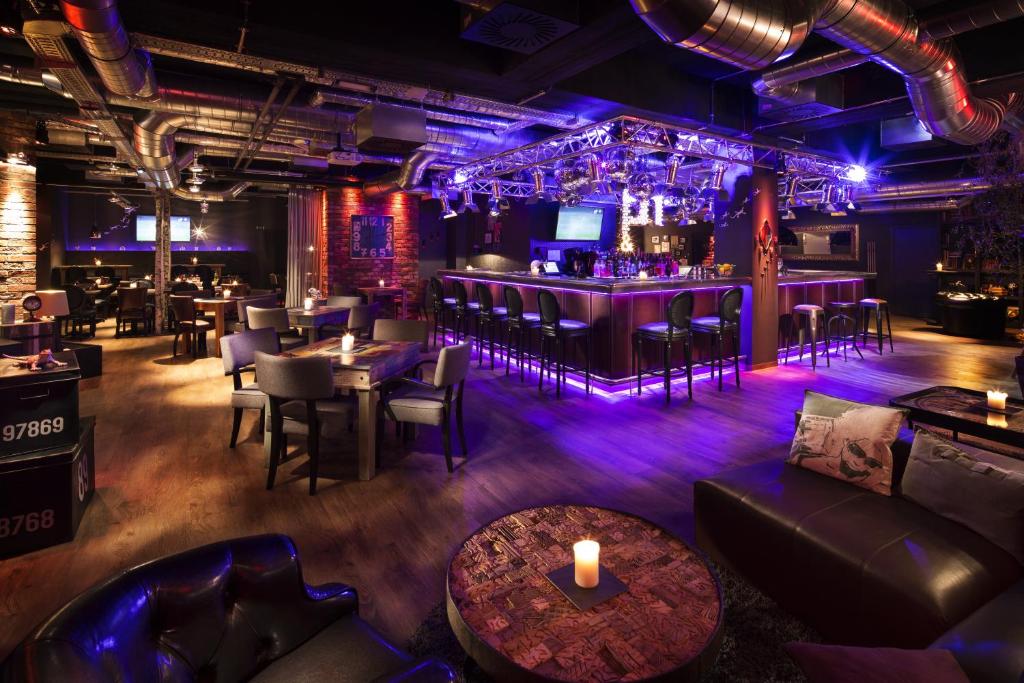 a restaurant with purple lighting and tables and chairs at pentahotel Liège in Liège