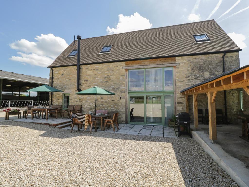 a building with a patio with tables and umbrellas at The Old Barn in Witney