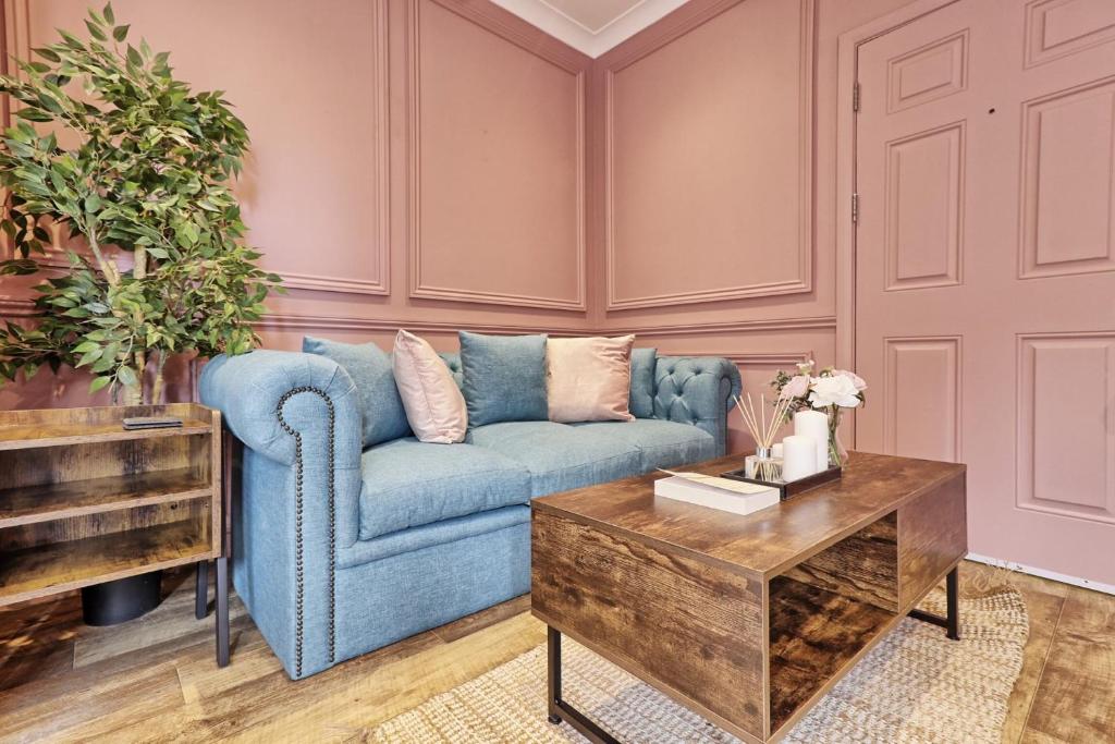 uma sala de estar com um sofá azul e uma mesa de centro em Plush Nest - Charming One-Bedroom Flat - Southend Stays em Southend-on-Sea