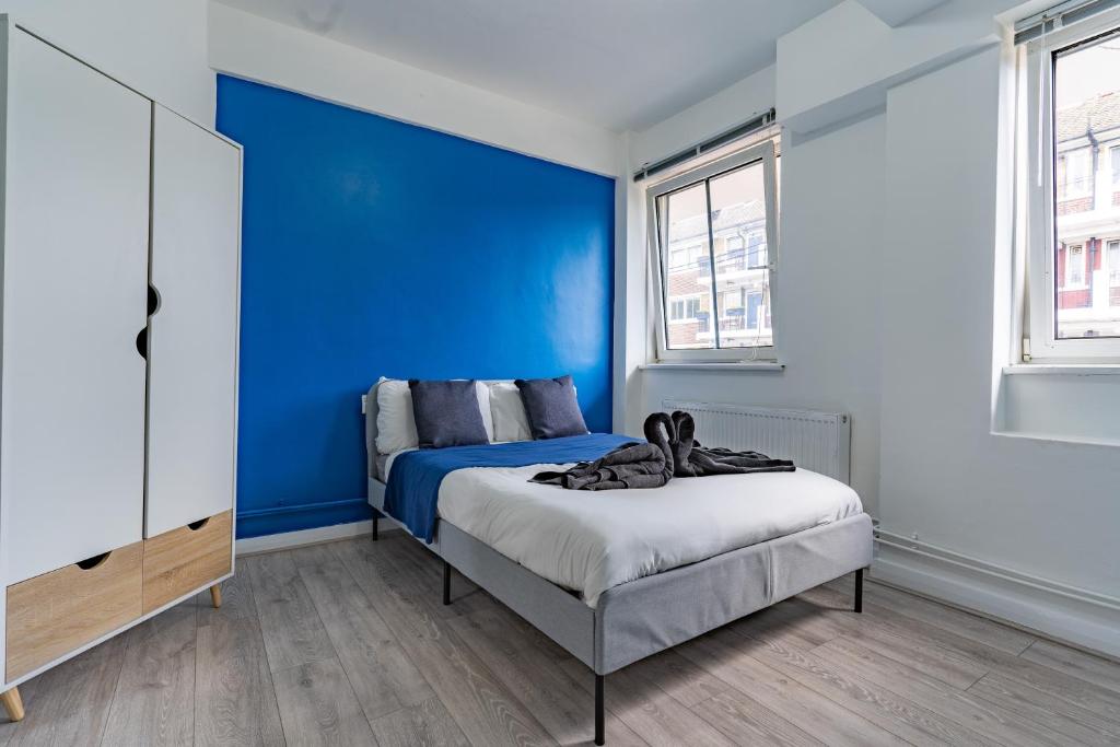 um quarto com uma parede azul e uma cama em Bright 1 Bed Flat near London Bridge em Londres