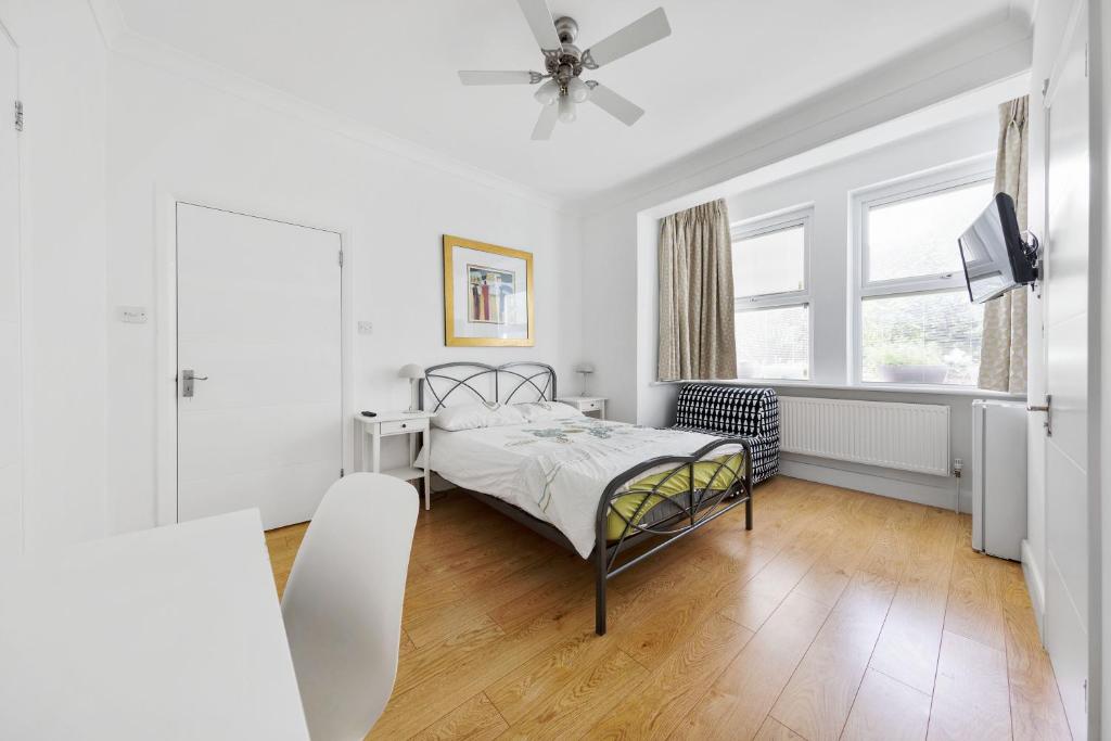 a white bedroom with a bed and a window at Tali’s House in London