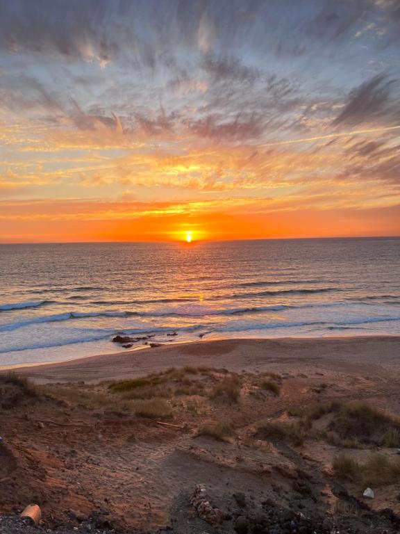a sunset on a beach with the ocean at The Paradise of ACHAKAR in Tangier