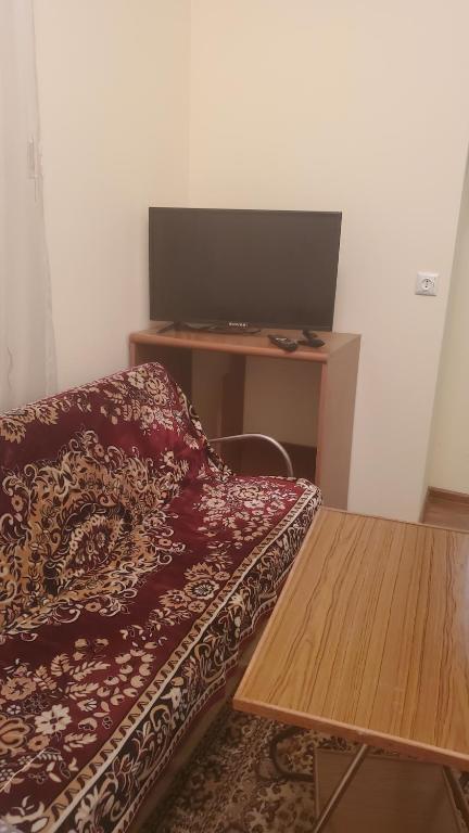 Cette chambre comprend un lit et un bureau avec une télévision. dans l'établissement Уютный дом, à Gyumri