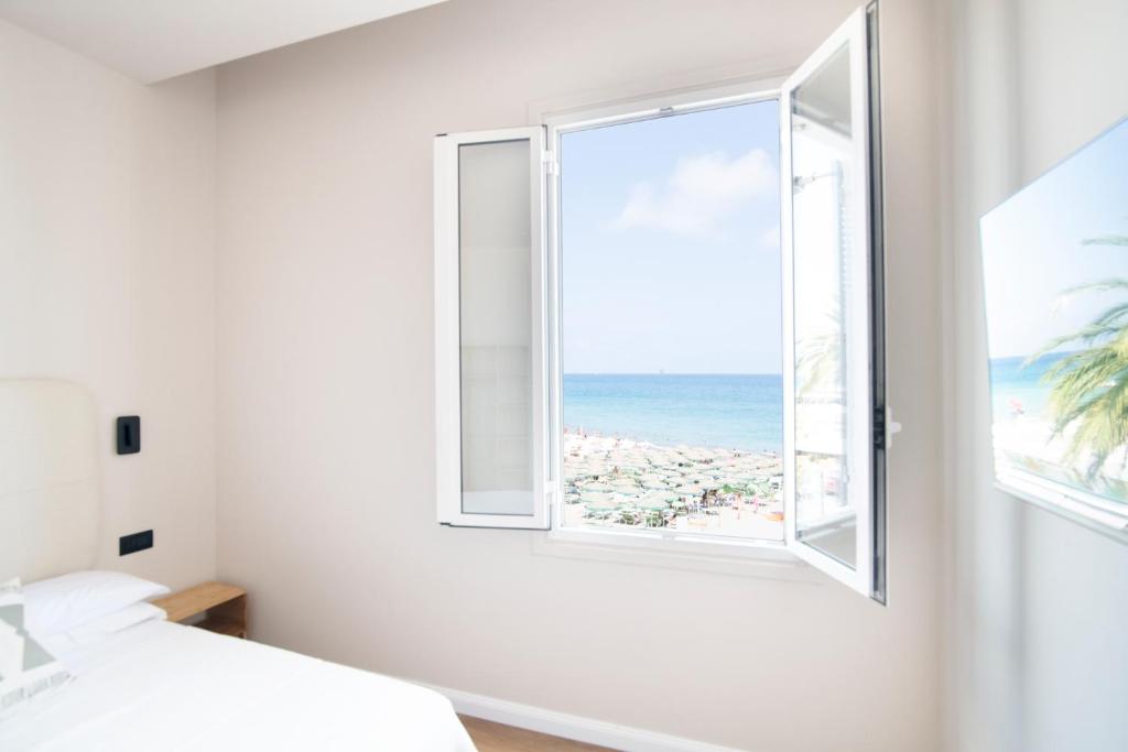 una camera da letto con finestra affacciata sull'oceano di Albium - Hotel Sul Mare ad Albenga