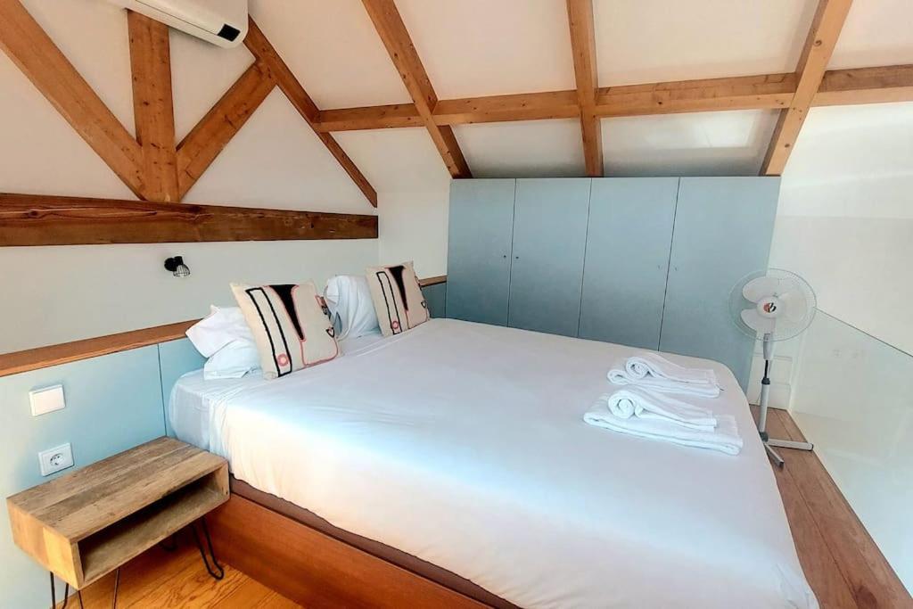 Cette chambre dispose d'un grand lit blanc et de plafonds en bois. dans l'établissement Oporto City View - Wow Duplex, à Porto