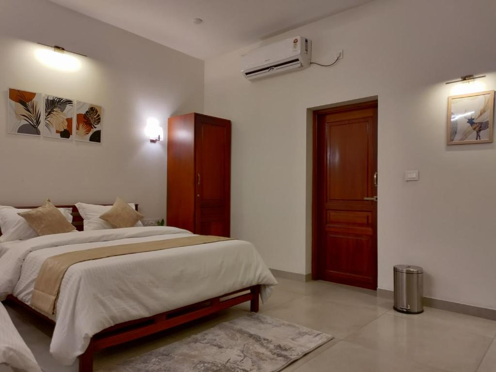 a bedroom with a large bed and a door at The Cana's Coorg in Ammatti