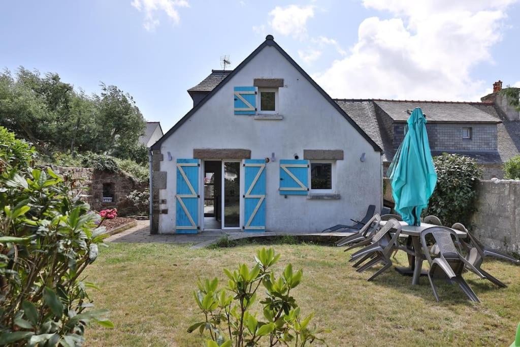 a house with blue doors and a table and umbrellas at Gîte Louannec - Ty Bleiz in Louannec