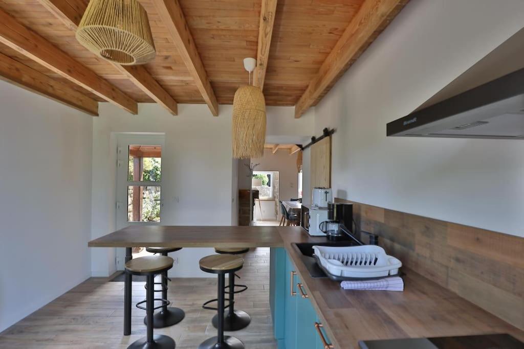 a kitchen with a wooden ceiling and a counter with stools at Gîte Louannec - Ty Bleiz in Louannec