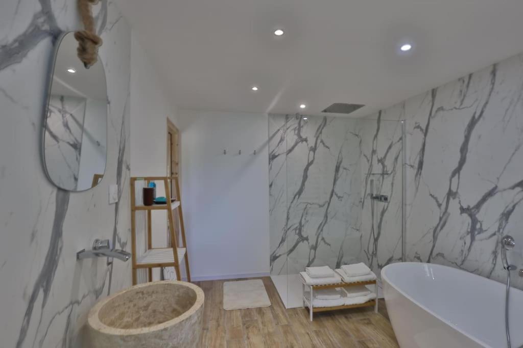 a bathroom with a tub and a marble wall at Gîte Louannec - Ty Bleiz in Louannec