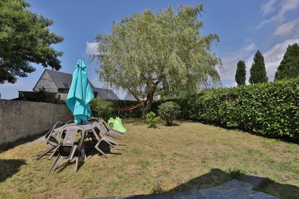 a table and chairs with an umbrella in a yard at Gîte Louannec - Ty Bleiz in Louannec