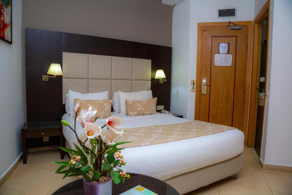 una camera con letto e vaso con fiori di Malak Hotel a Rabat