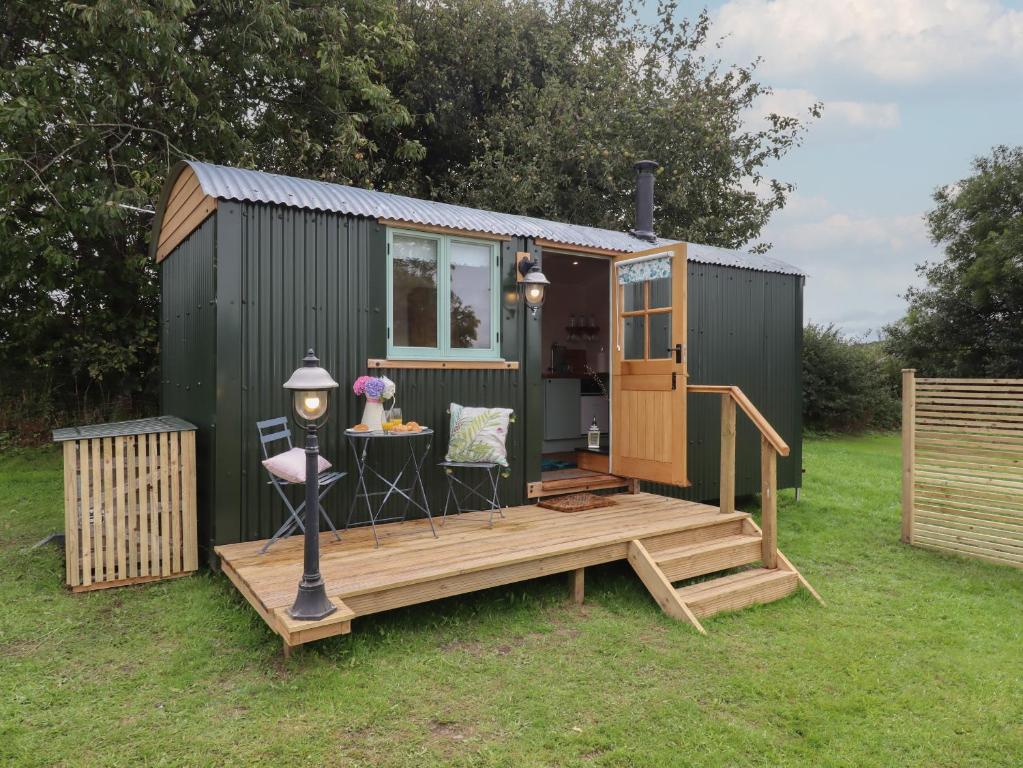 a green tiny house with a wooden deck at Lottie's Hut in Okehampton