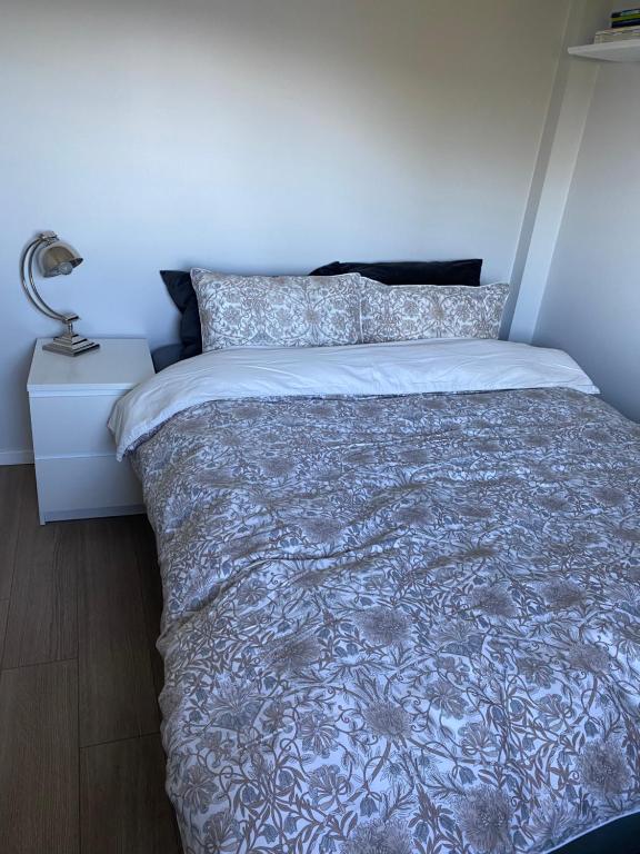 ein Bett mit einer blauen und weißen Tagesdecke und einem Nachttisch in der Unterkunft Råket 3 in Viggja