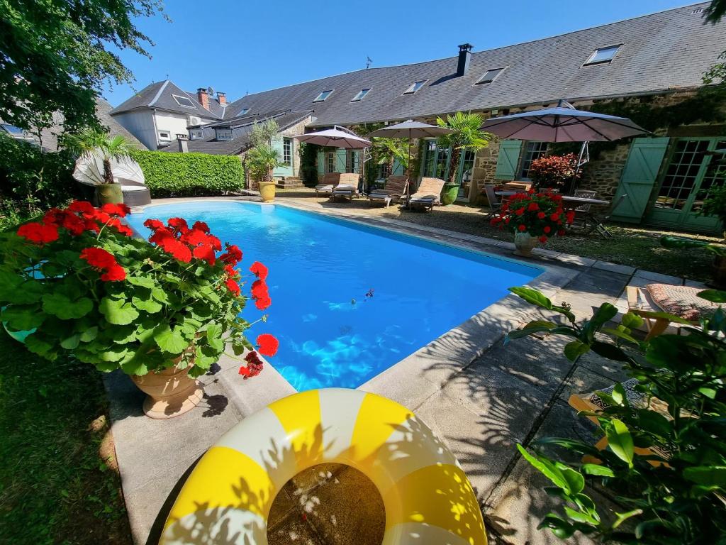 a swimming pool with red flowers in a yard at Maison d'hôtes Les jardins Saint Eloi in Le Lonzac