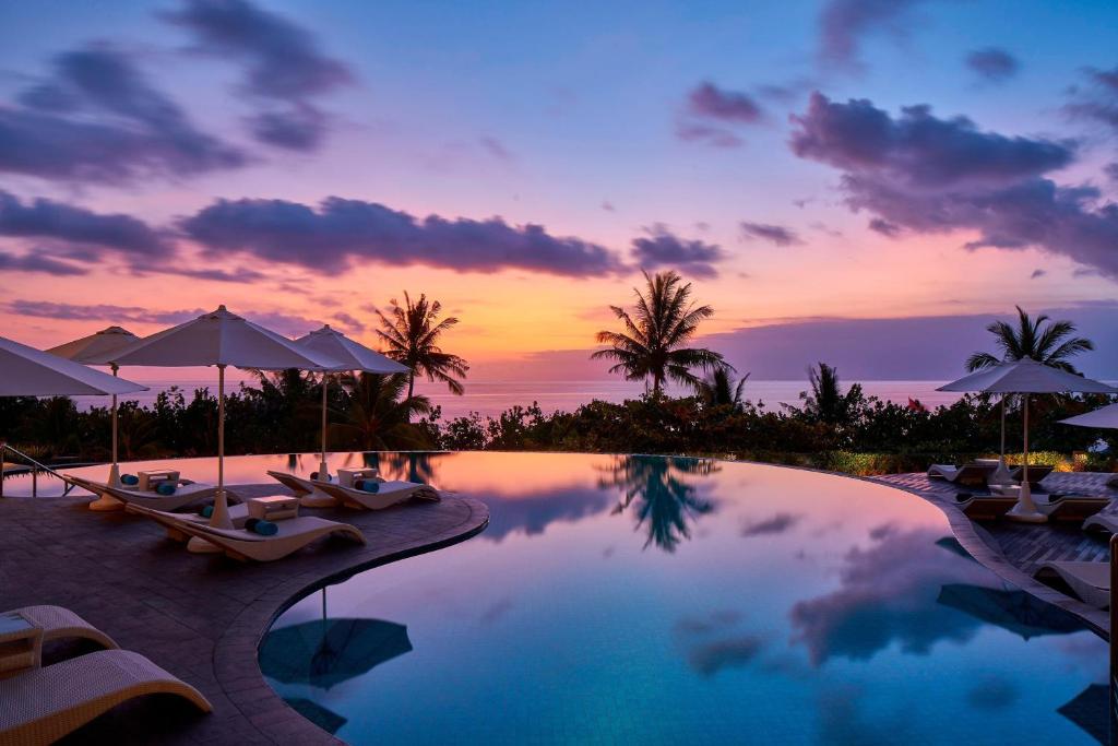 Sheraton Bali Kuta Resort في كوتا: مسبح مع كراسي ومظلات في المنتجع