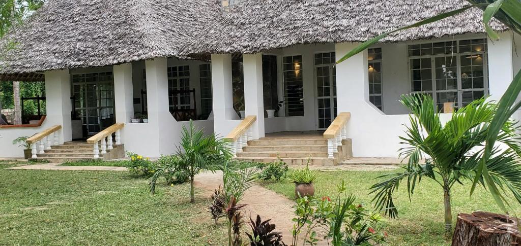 a house with a thatched roof and a yard at Mangos Villas - Chiara in Kilifi