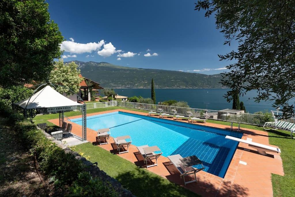 a swimming pool with chairs and a view of the water at Villa Aurora- Villa esclusiva con piscina e splendida vista lago in Gargnano