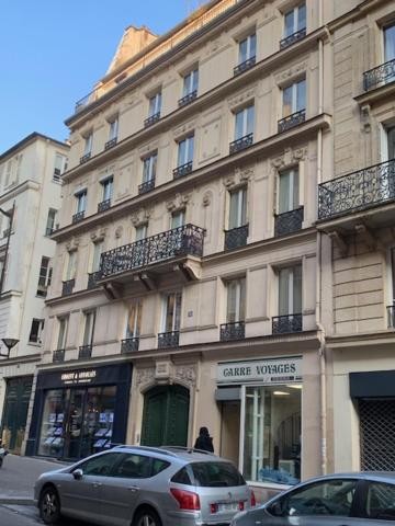 Deux voitures garées devant un grand bâtiment dans l'établissement Studio PARIS 75010, à Paris