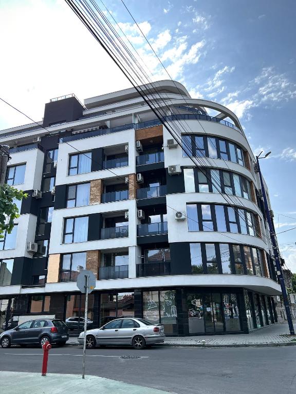 a large building with cars parked in front of it at Ultra Lux Apartment Free Underground Secure Parking in Pazardzhik