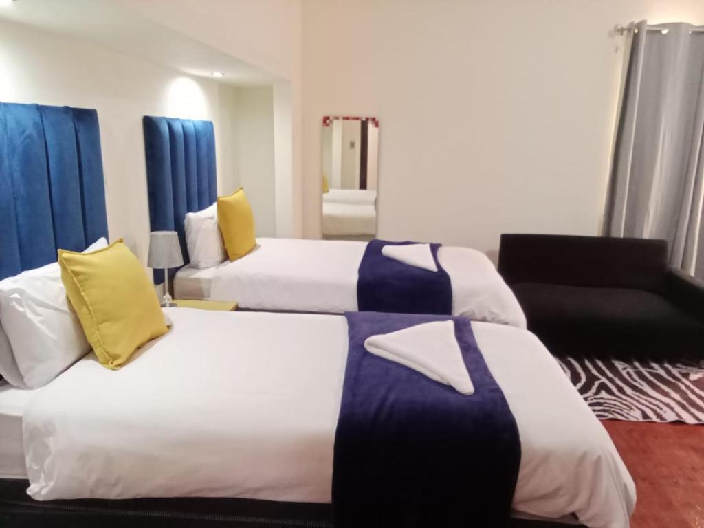 a hotel room with two beds and a chair at Safi Suites and Conference Centre in Mthatha