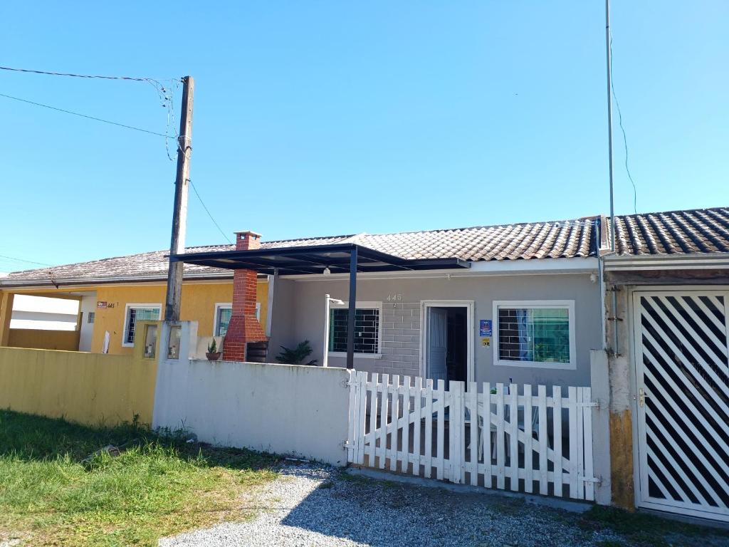 a house with a white fence and a gate at Excelente casa na praia em Matinhos PR. 600 metros da praia. in Matinhos