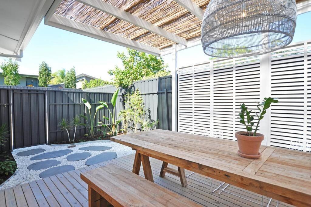 um pátio com uma mesa de madeira e um vaso de plantas em Pine at Arlos Glenelg South em Glenelg