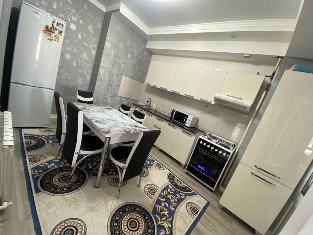 Una cocina con mesa y sillas y un refrigerador. en 2 room apartment Цум Айчурок, en Bishkek