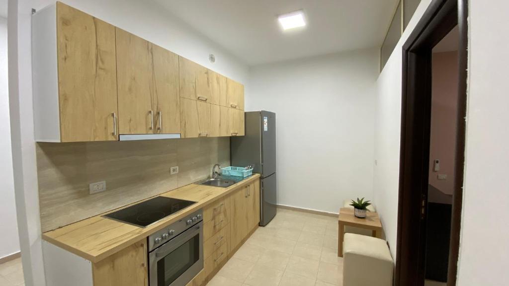 a kitchen with wooden cabinets and a stainless steel refrigerator at Anna´s apartament in Lushnjë