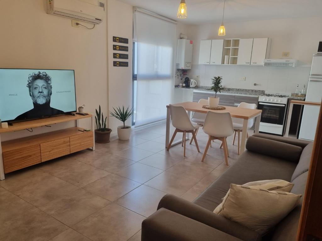 ein Wohnzimmer mit einem Sofa, einem TV und einem Tisch in der Unterkunft PRISMA CUARENTA in Villa Carlos Paz