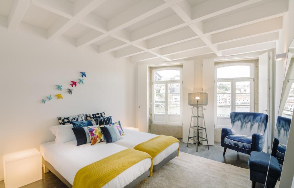 a white bedroom with a bed and a blue chair at Oporto Welcome Apartments - Ribeira Negra in Porto
