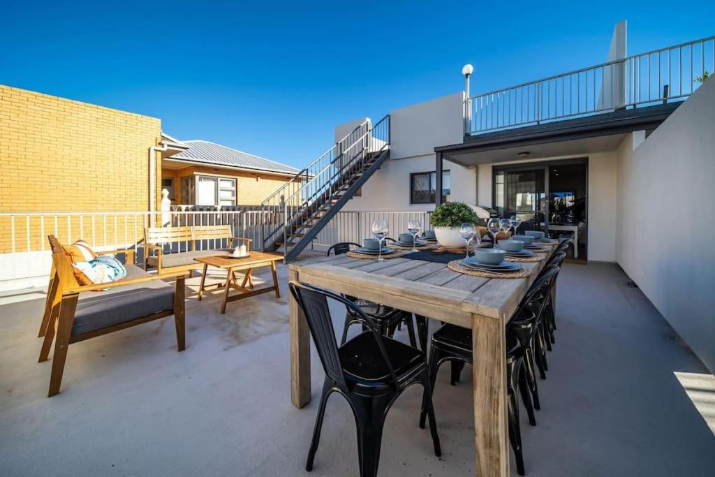 a wooden table and chairs on a patio at Higher Ground on Seaview - Rooftop Coastal Escape in Henley Beach South