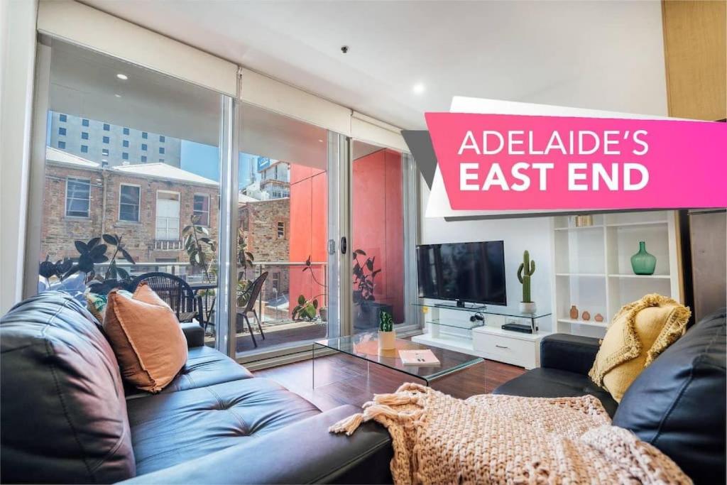 ein Wohnzimmer mit einem blauen Sofa und einem Fernseher in der Unterkunft Tropicana on Bent Adelaide in Adelaide