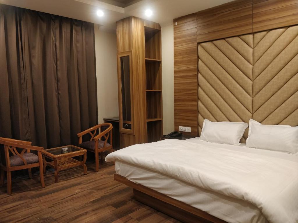 a bedroom with a large bed with a wooden headboard at Pinnacle Vesta Botique Stay in Mussoorie