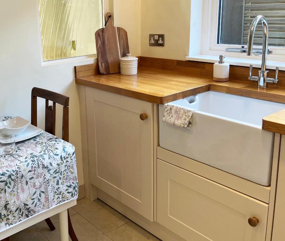 a kitchen with a sink and a table with a chair at Traditional 2 bedroom Cottage in Stratford-upon-Avon
