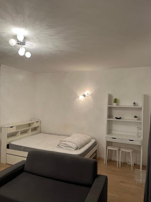 une petite chambre avec un lit et un canapé dans l'établissement Appartement proche de paris, à Saint-Cloud