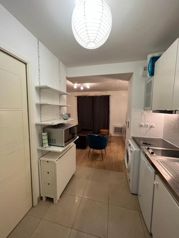 uma cozinha com armários brancos e uma grande luminária em Appartement proche de paris em Saint-Cloud