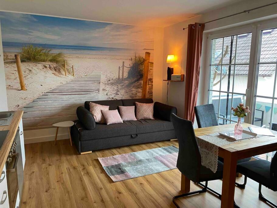 a living room with a couch and a painting of a beach at Kleines Glück Grömitz (ehemals Deichperle) in Grömitz